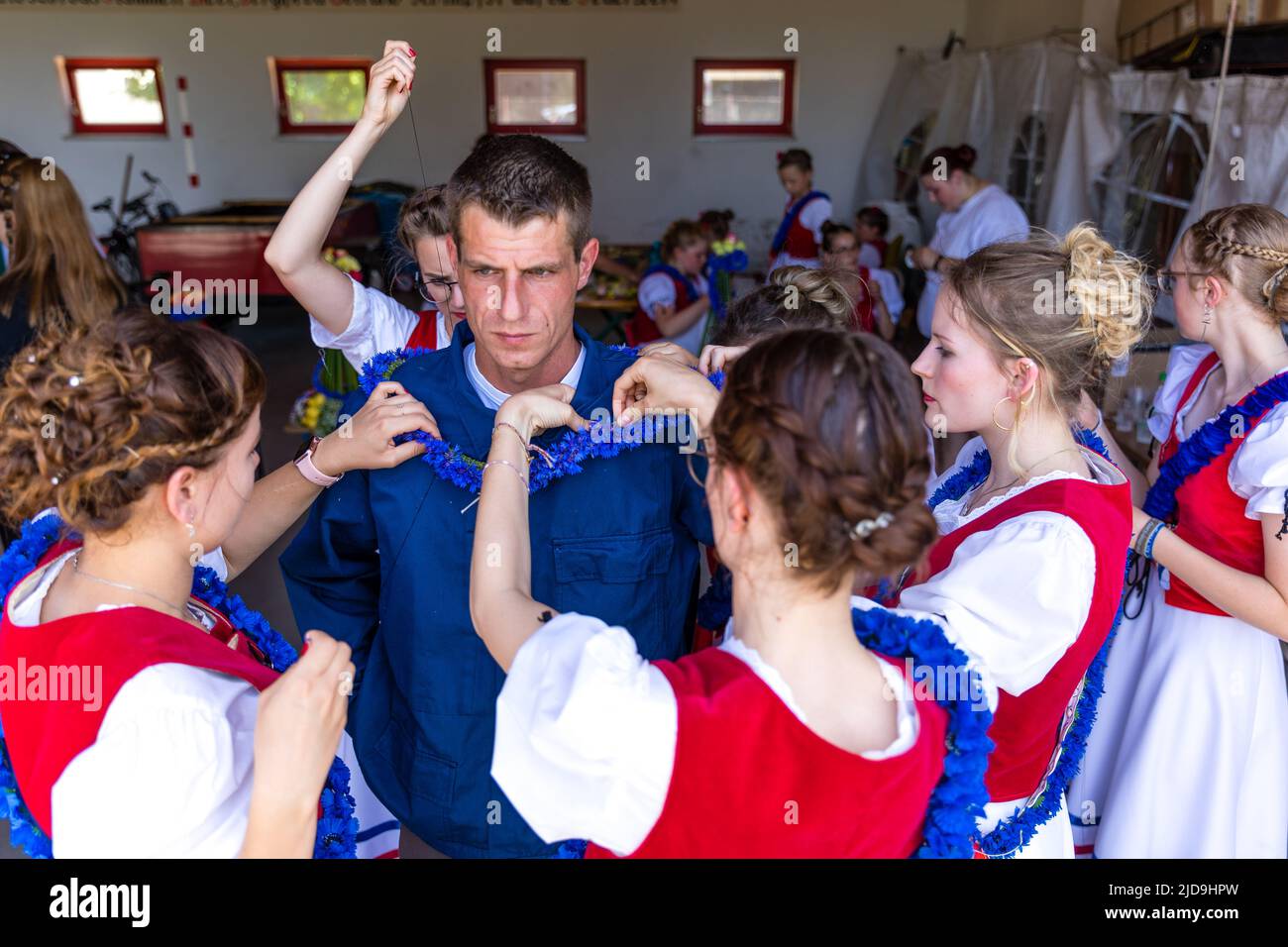 19. Juni 2022, Brandenburg, Casel: In einer etwa 90-minütigen Prozedur schmücken junge Frauen und Mädchen aus dem Kreis Drebkauer von Casel Tobias Richter, den Johann, während der Johannisreiten mit Blumen. Während des Johannisreitens wird ein Bursche - Johann - aus Casel von jungen Frauen aus dem Dorf mit Seerosen, Binsen, Kornblumen und anderen Pflanzen geschmückt und reitet gemeinsam mit seinen Gefährten. Die Gefährten reduzieren sich jedes Mal, wenn sie durchfahren werden. Besucher des Festivals versuchen Teile von St. Johns Kopf- und Körperschmuck zu schnappen - diese werden gehalten und versprechen eine reiche Ernte für die Stockfoto