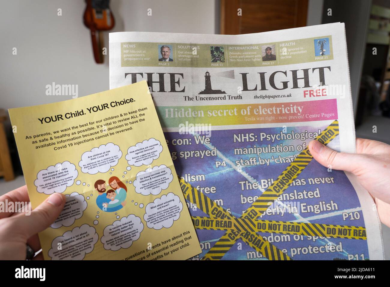 Ein Impfzettel gegen Covid-19 Coronavirus und eine Kopie von The Light - einer kostenlosen Zeitung zur Verschwörungstheorie - in den Händen eines Mannes. VEREINIGTES KÖNIGREICH Stockfoto