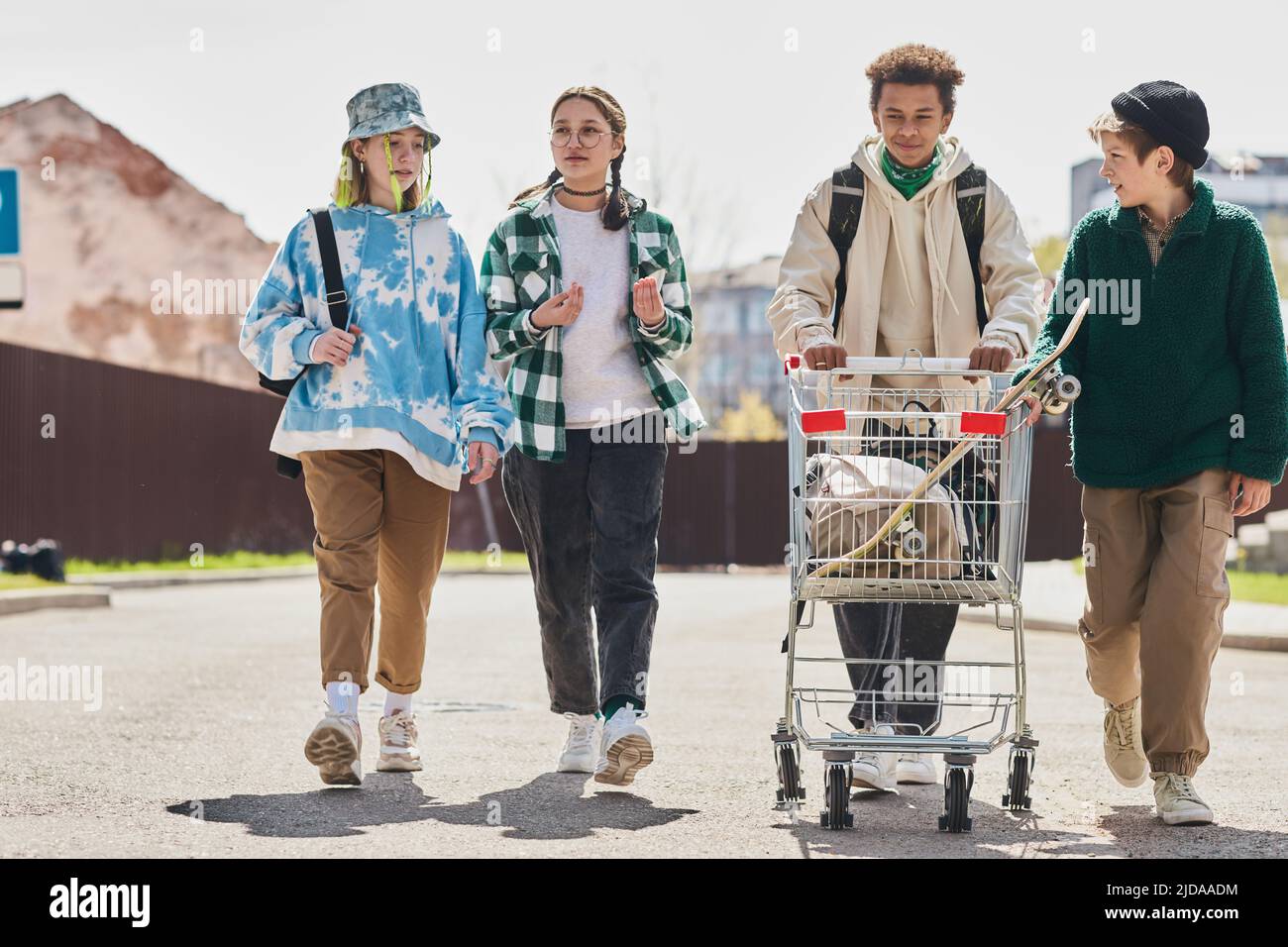 Eine Gruppe von Teenagern, die die Straße entlang gehen und den Einkaufswagen mit ihren Sachen tragen Stockfoto