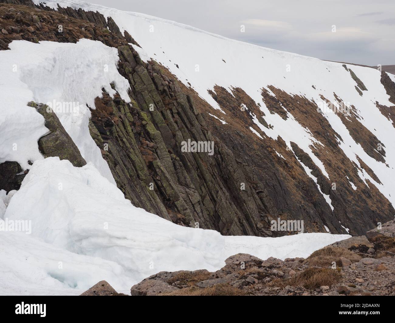 Blick über den Gipfel des Great Gully nach Carn na Criche. Schöne Felsformationen & Erosionsrisse des Granits. Trübe Wolken am Himmel und Flecken von Schnee. Stockfoto