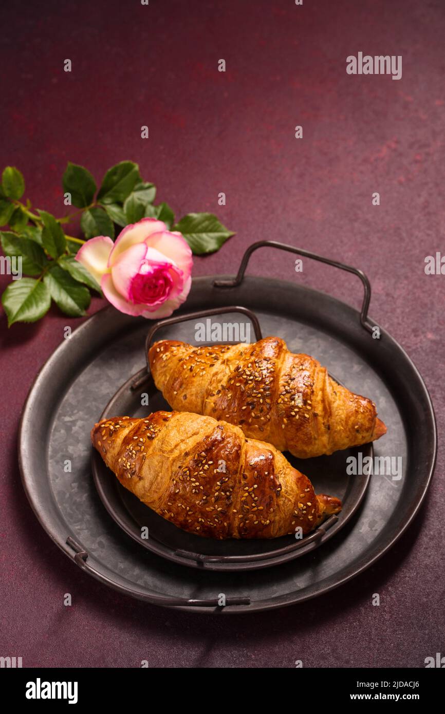 Knusprige, rockige Croissants in einem antiken Metalltablett auf einem burgunderroten Hintergrund, Draufsicht Stockfoto