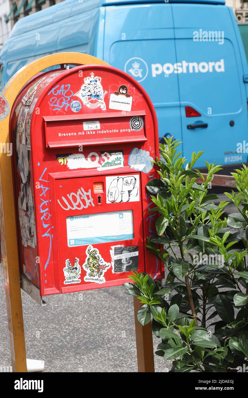 Kopenhagen, Dänemark - 14. Juni 2022: Eine rote dänische Postdienstleistung dropboxed vor dem Postnord-Paketzustellwagen verwüstet. Stockfoto