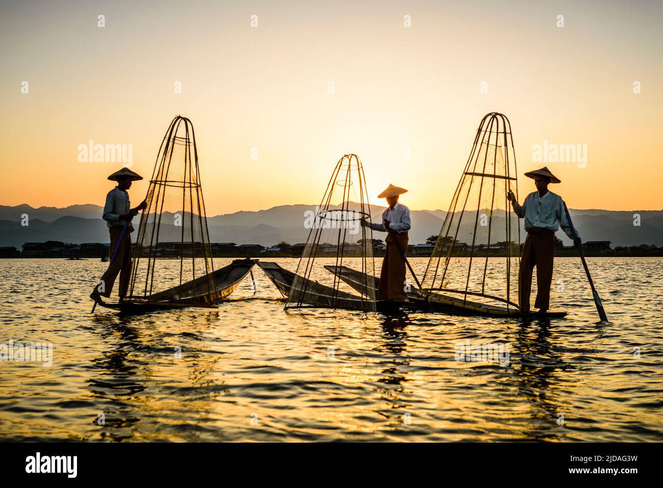 Drei Fischer fischen auf dem Inles-See mit traditionellen kegelförmigen Fischernetzen. Stockfoto