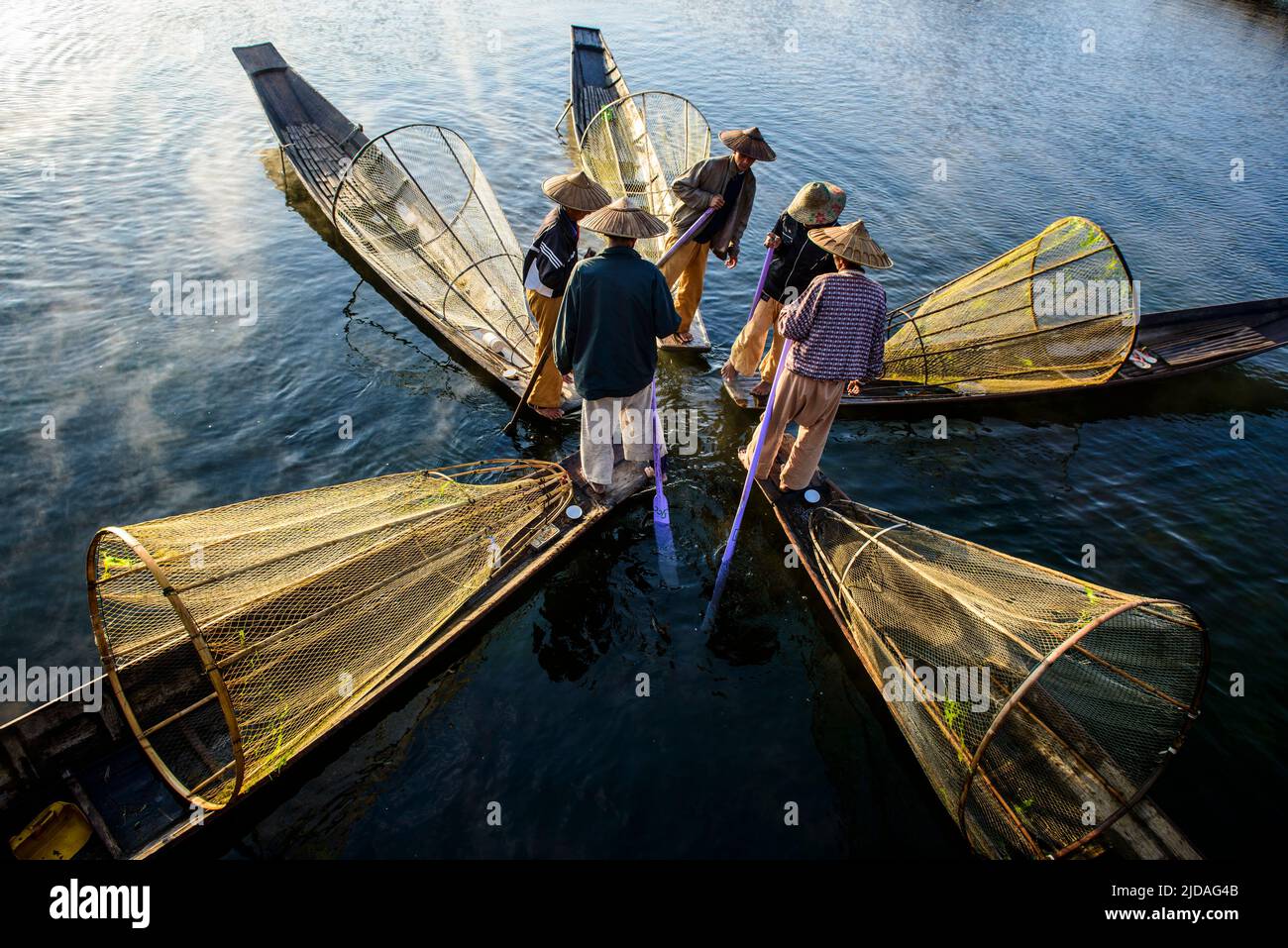 Fünf Fischer auf traditionellen Booten mit konischen Fischernetzen. Stockfoto