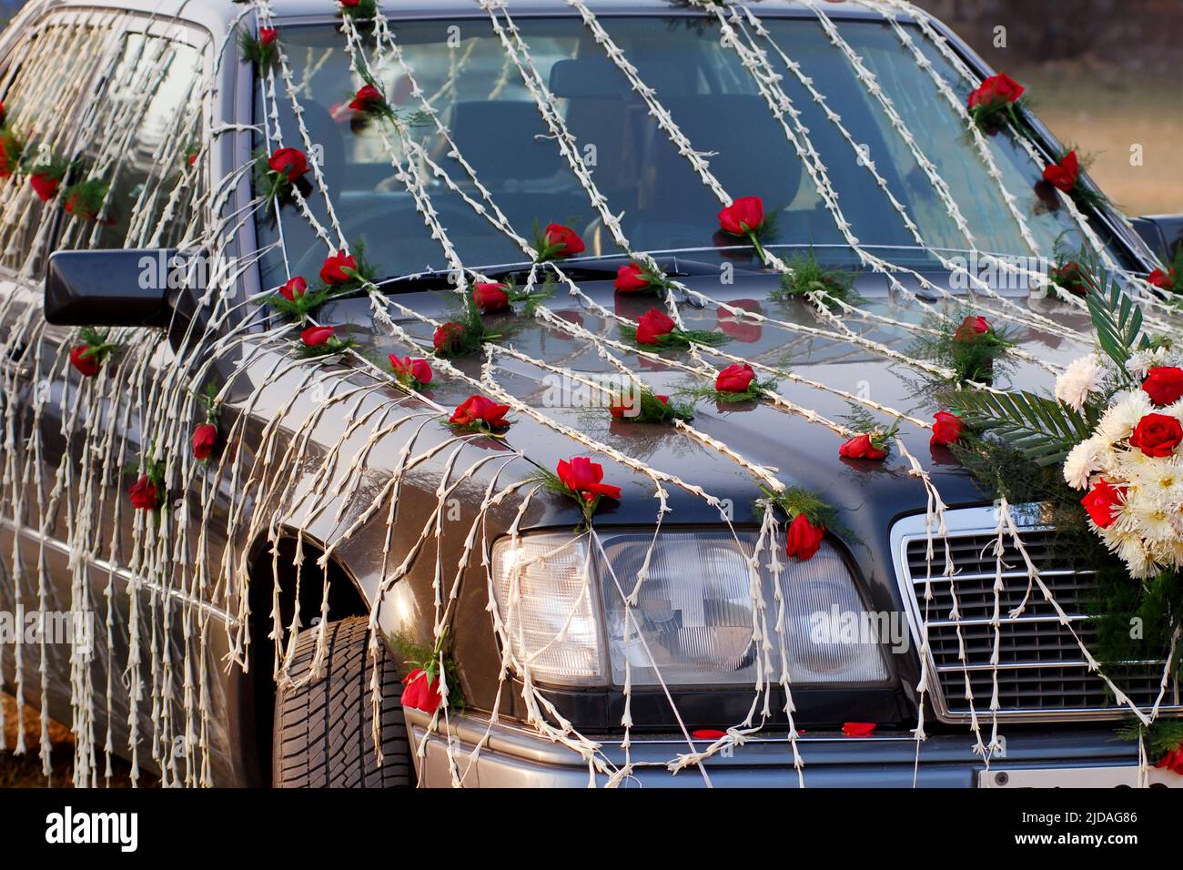 Ein Hochzeitsauto mit roten und weißen Blumen. Stockfoto