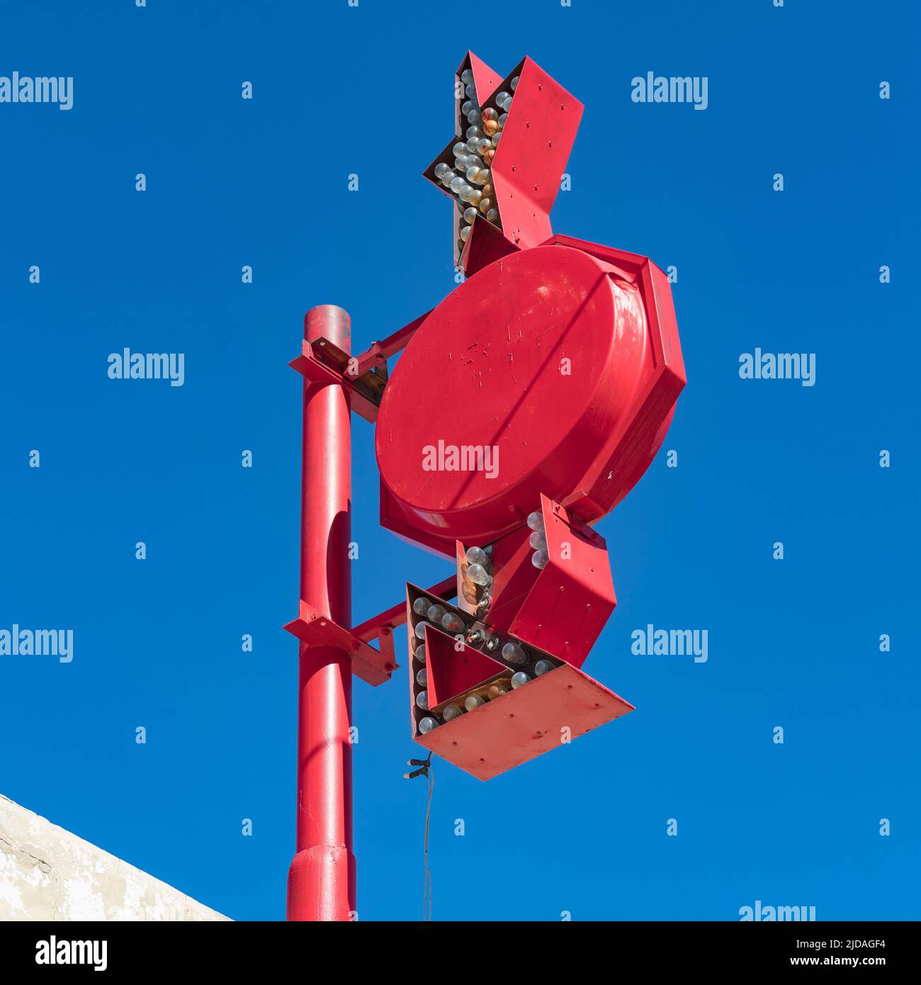 Ein Werbeschild mit Pfeilen und Lichtern auf einem Pfosten gegen den blauen Himmel. Stockfoto