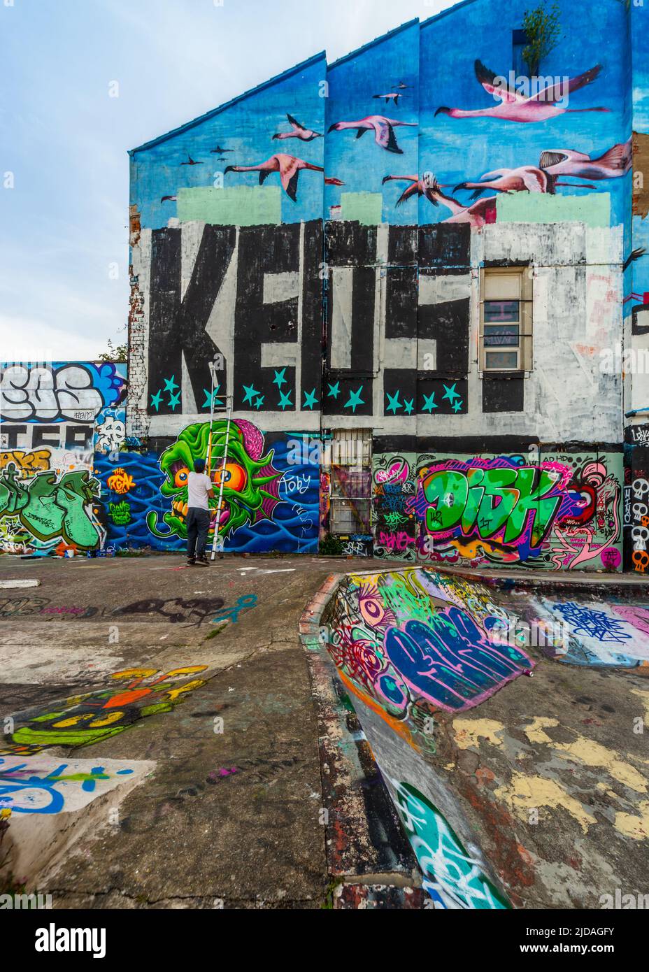 Mr KEOS, ein Straßenkünstler, der Farbe auf die Wand des Skateparks in der Jamaica Street, Baltic Triangle, Liverpool, Großbritannien, aufgetragen hat Stockfoto