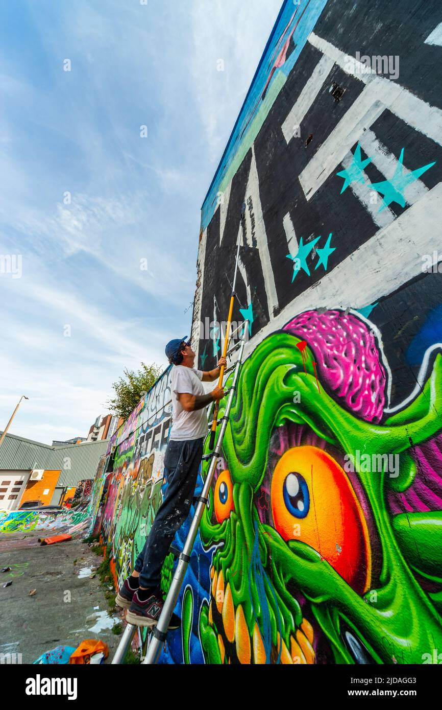 Mr KEOS, ein Straßenkünstler, der Farbe auf die Wand des Skateparks in der Jamaica Street, Baltic Triangle, Liverpool, Großbritannien, aufgetragen hat Stockfoto
