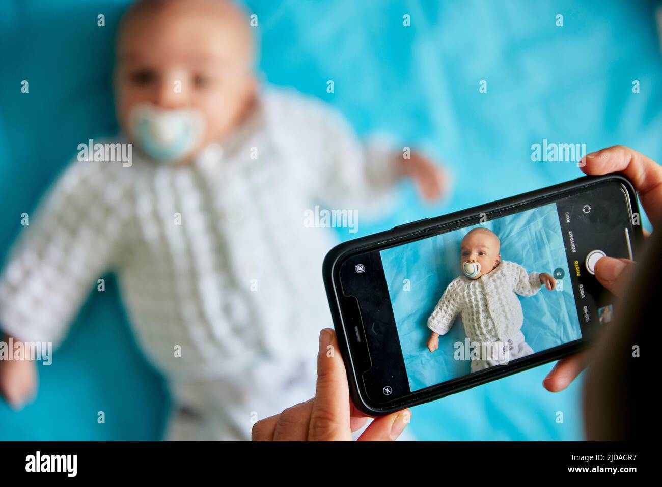 Eltern fotografieren das Kind, das sich mit dem Smartphone hinlegt, aufgenommen von oben Stockfoto