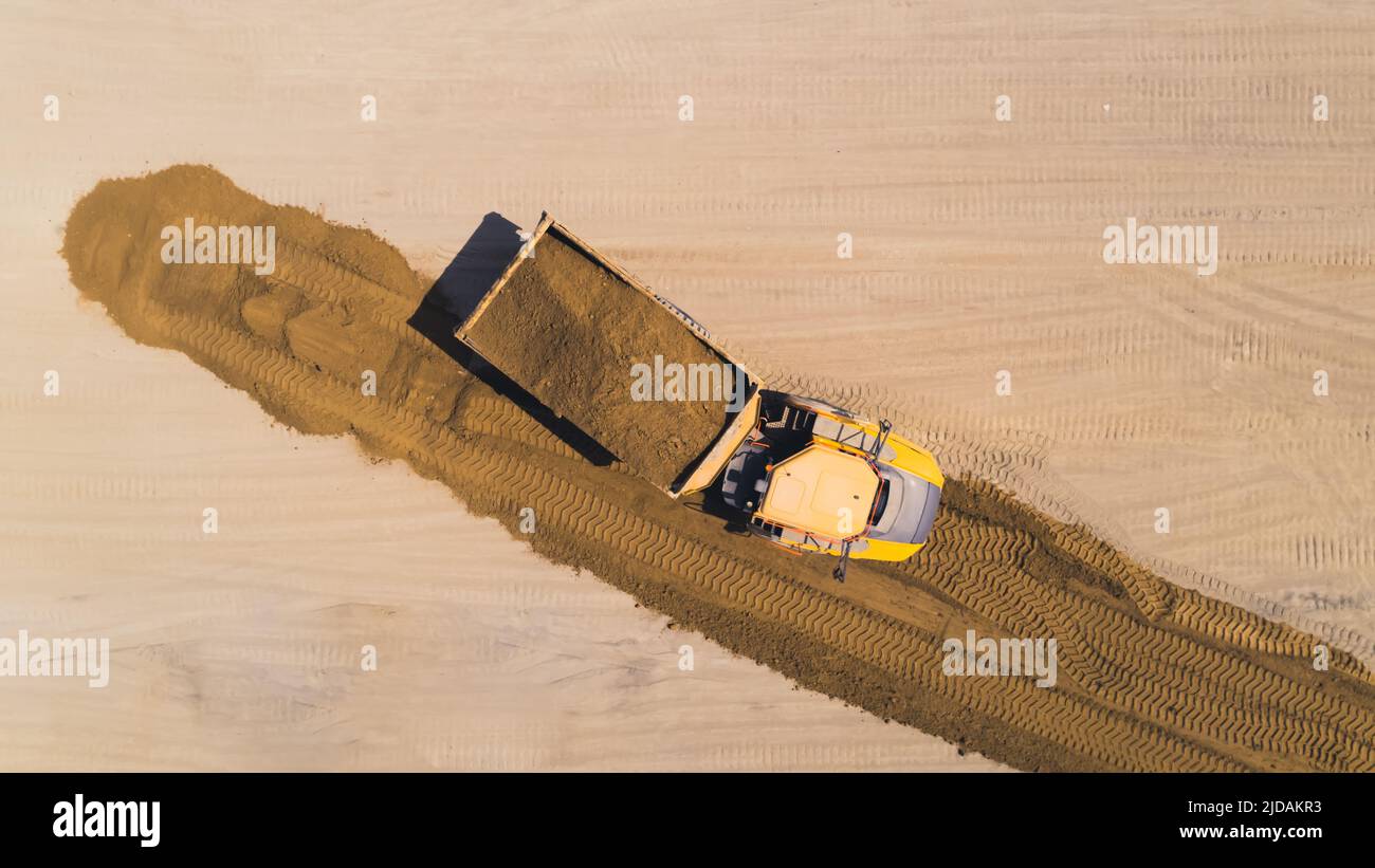Ein gelber, riesiger, professioneller Kipper, der mit einem Sandhaufen zurückzieht. Drohne geschossen. Hochwertige Fotos Stockfoto
