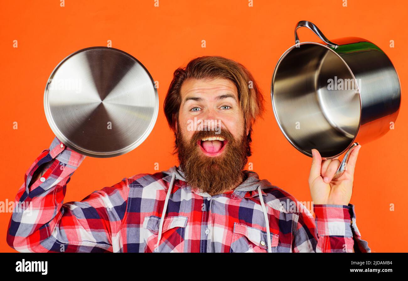 Glücklicher bärtiger Mann mit Topf und Deckel. Männlicher Koch mit Kochtopf. Kochen von Speisen. Küchenutensilien. Stockfoto