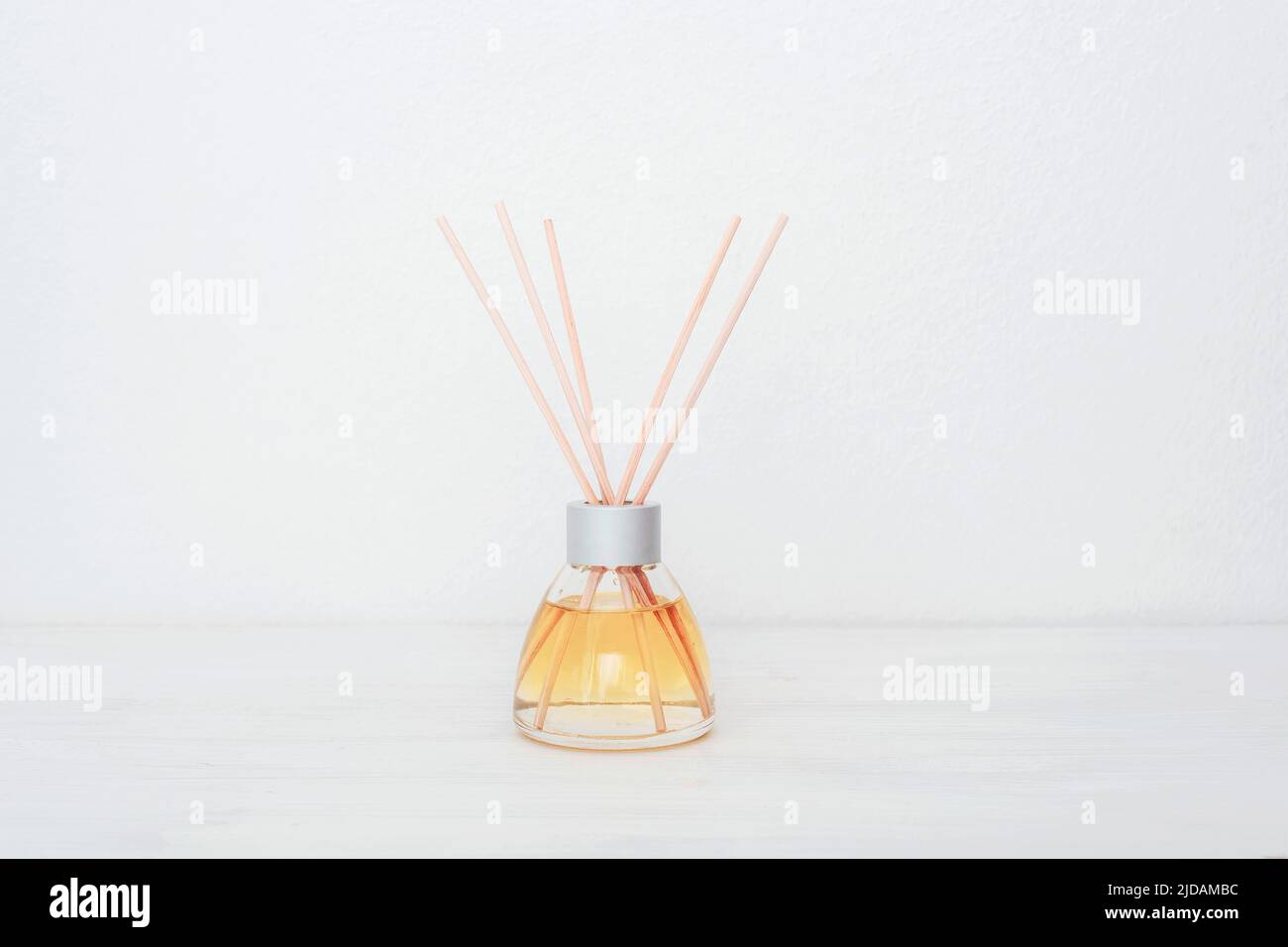 Glasflasche mit Aroma-Diffusor auf weißem Hintergrund. Minimalistisches Design der Inneneinrichtung. Nahaufnahme, Kopierbereich. Stockfoto