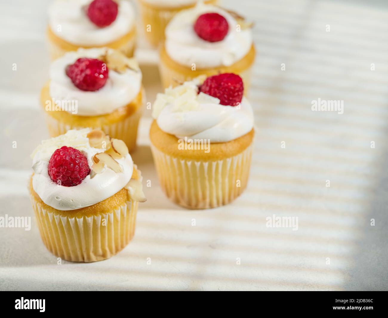 Appetitliche Muffins mit Rahm und Himbeeren. Isoliert auf weißem Hintergrund. Süßes Essen, viele Kalorien. Urlaub, Geburtstag. Restaurant, Hotel, Café, Stockfoto