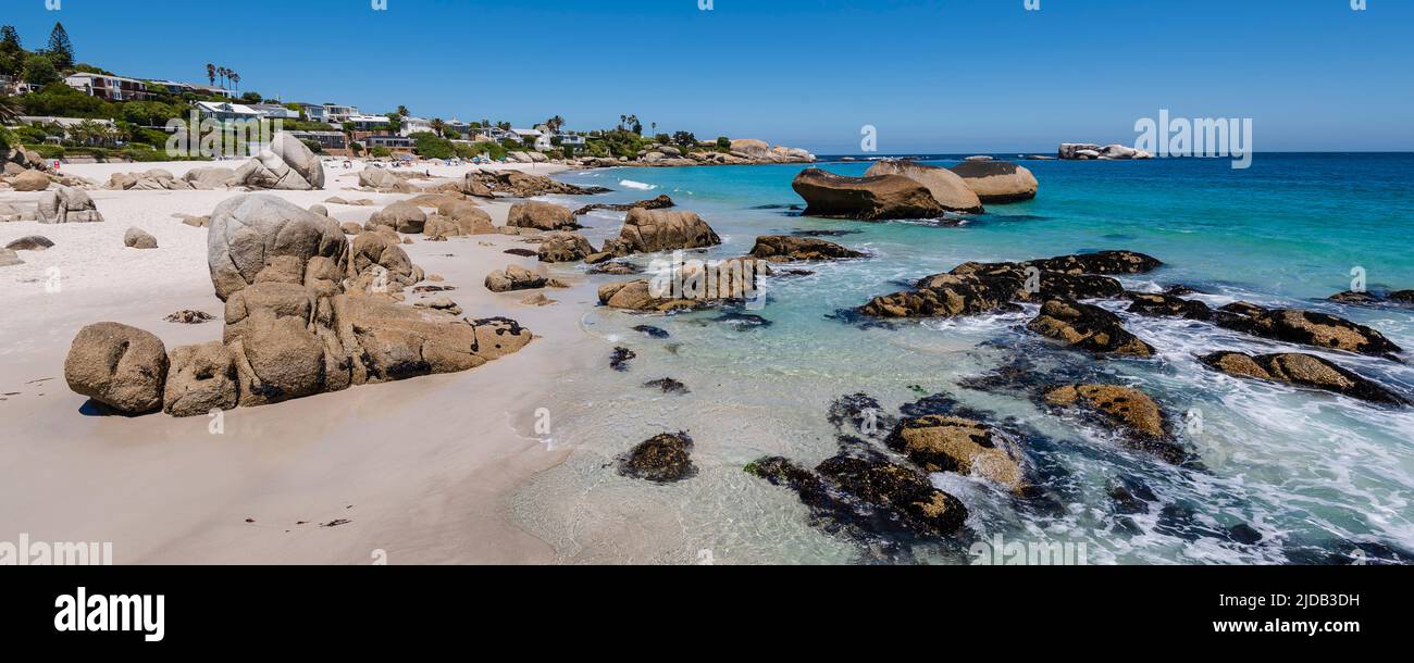 Felsiges Ufer mit großen Felsblöcken und Strandhäusern am Atlantik in Clifton Beach; Kapstadt, Westkap, Südafrika Stockfoto