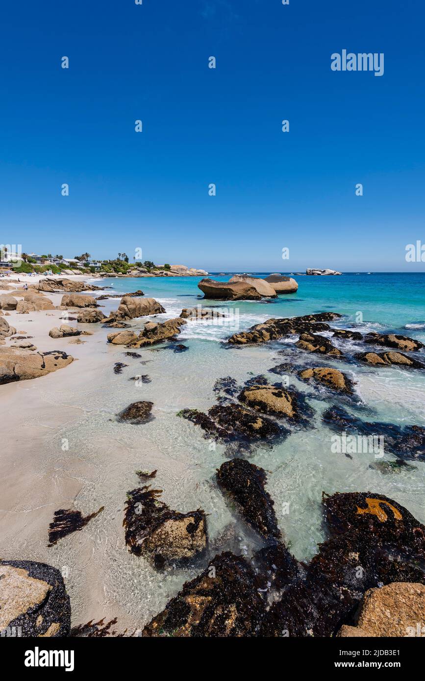 Felsiges Ufer mit großen Felsblöcken und Strandhäusern am Atlantik in Clifton Beach; Kapstadt, Westkap, Südafrika Stockfoto