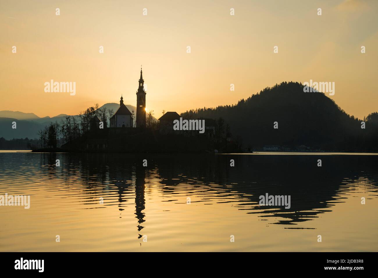 Silhouette von Kirche und anderen Gebäuden am Bleder See bei Sonnenaufgang; Bled, Slowenien Stockfoto