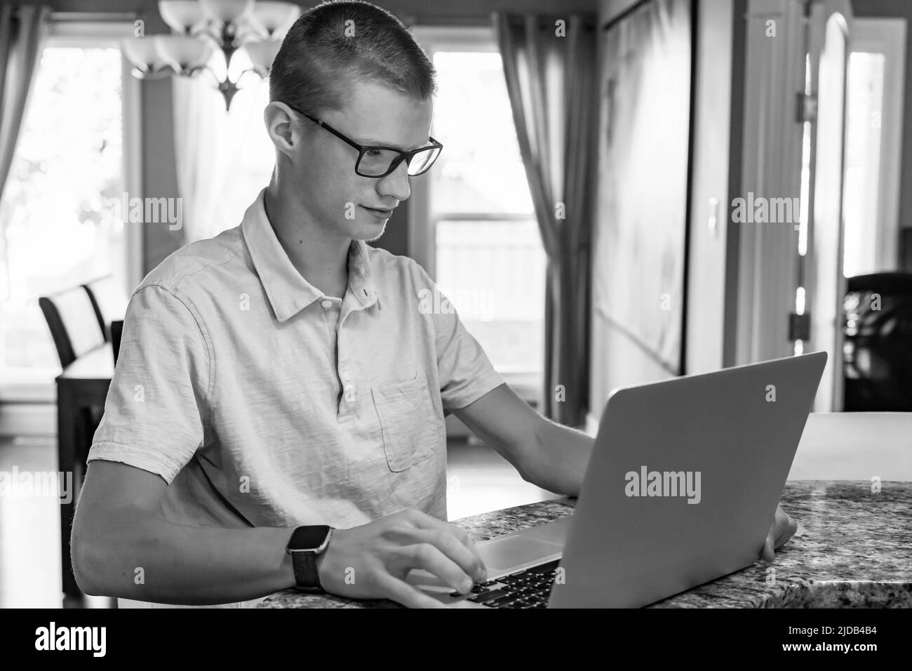 Der junge Mann verwendet zu Hause einen Laptop; Edmonton, Alberta, Kanada Stockfoto