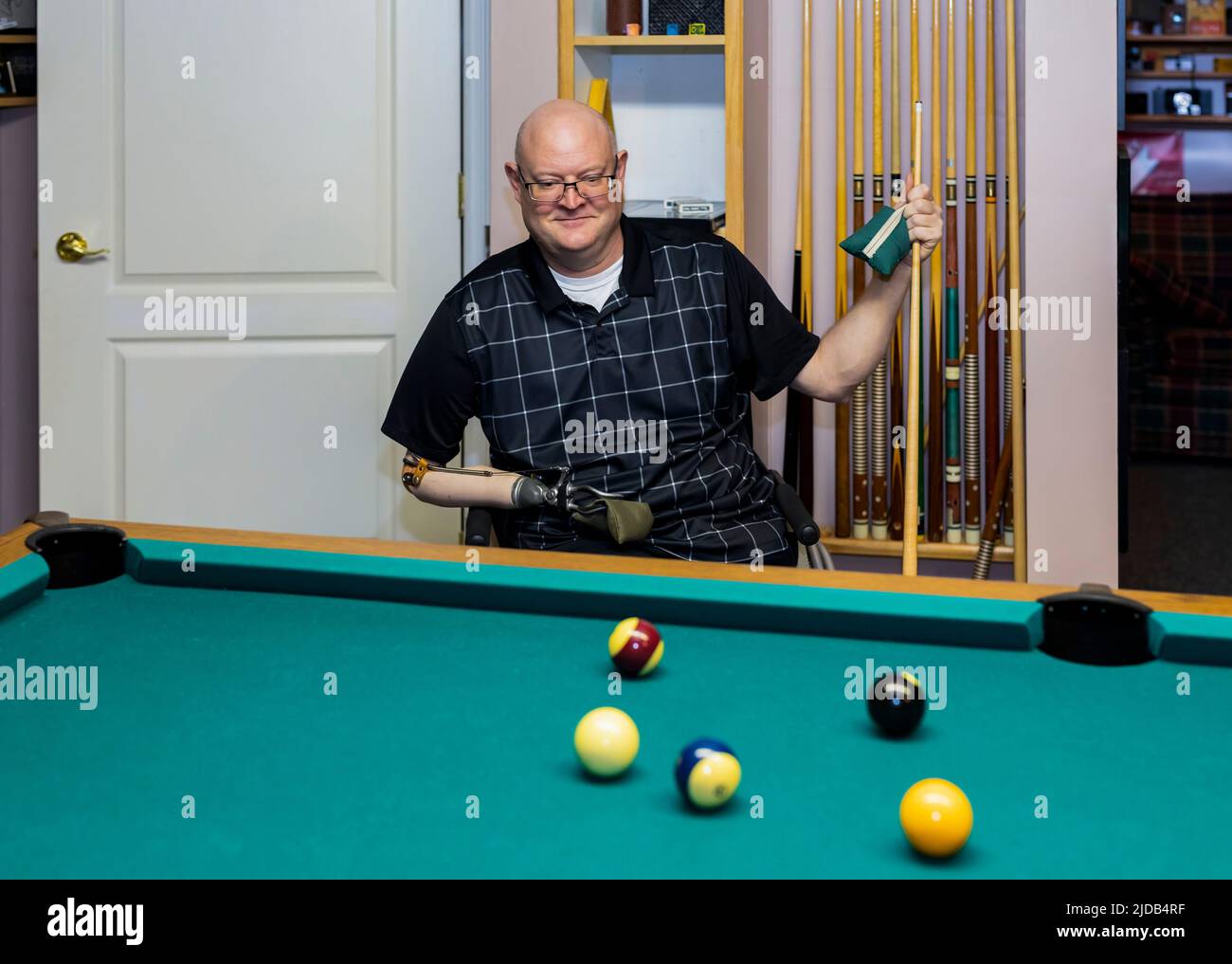 Ein Mann mit zwei Gliedmaßenamputationen, der zu Hause Billard spielt Albert, Alberta, Kanada Stockfoto