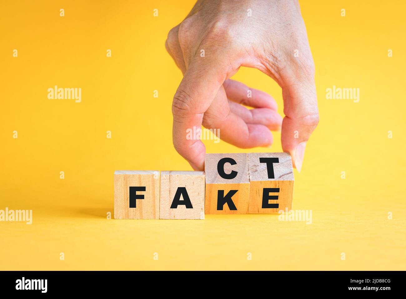 Handliche Spiegeln Holzwürfel Block, von der Tatsache, um gefälschte Formulierung. Auf gelbem Hintergrund. Stockfoto