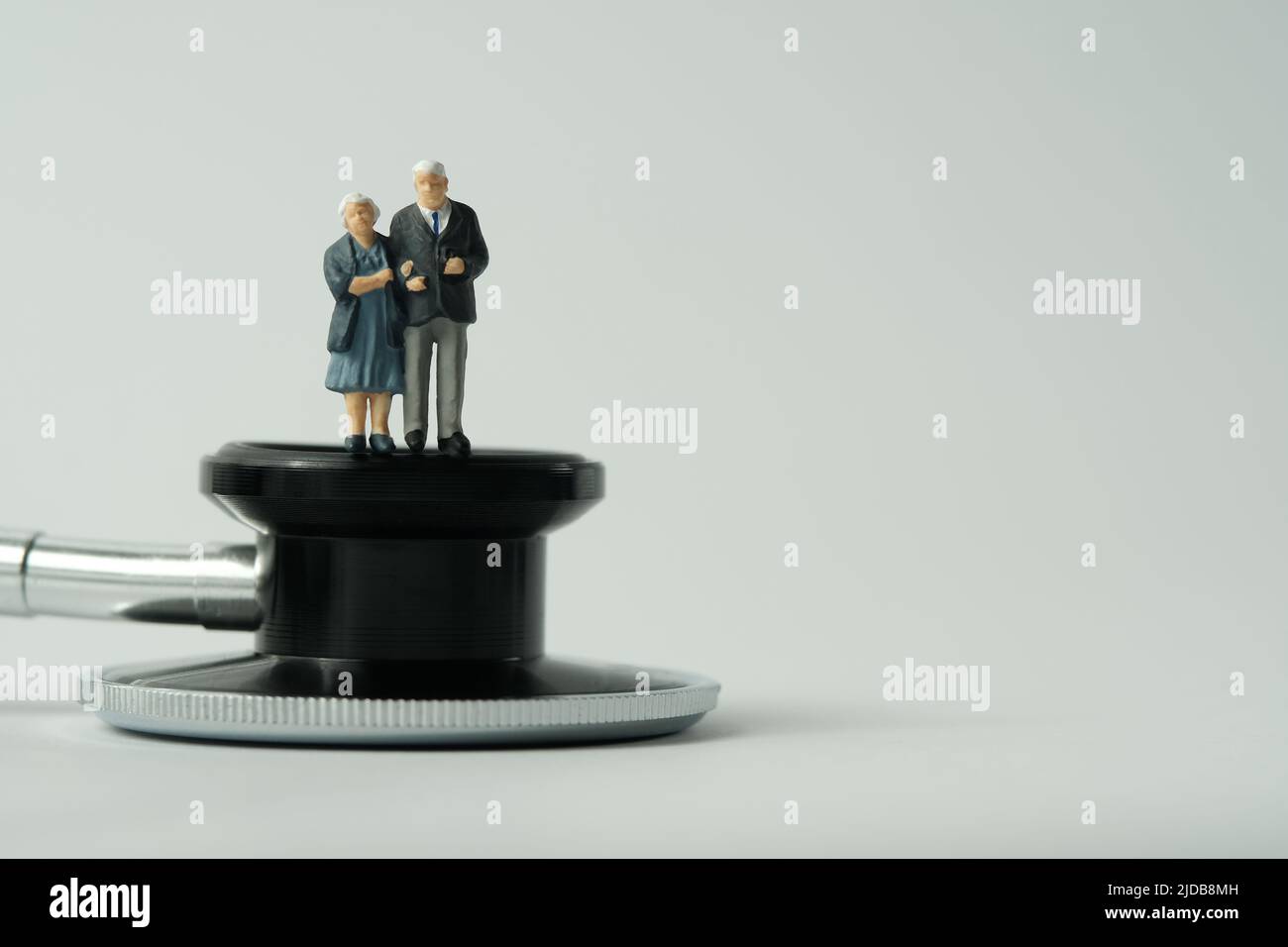 Miniatur Menschen Spielzeug konzeptuelle Fotografie. Älteres Paar, das medizinische Untersuchungen macht und über Stethoskop steht. Isoliert auf weißem Hintergrund. I Stockfoto