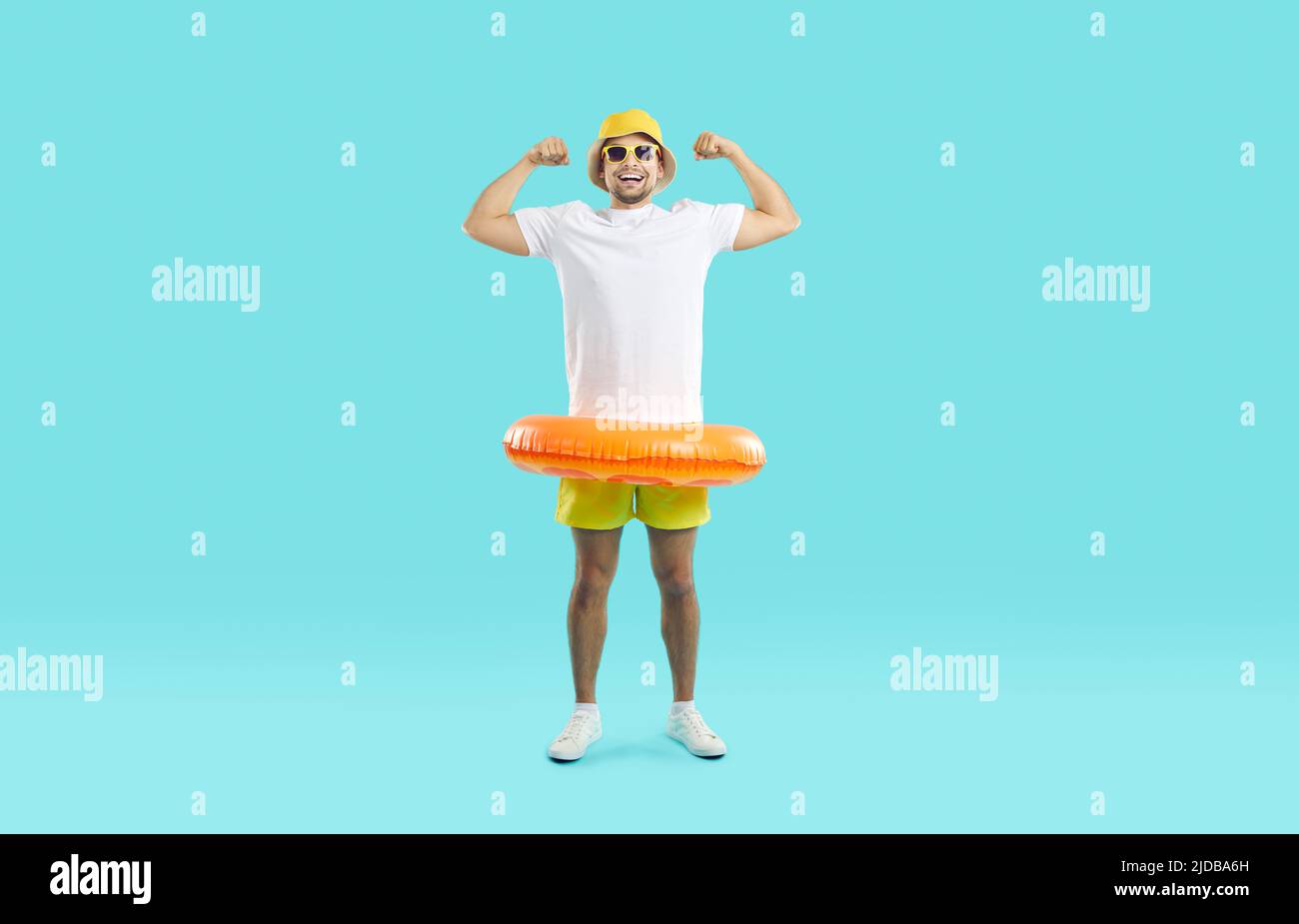Lustiger Mann mit orangefarbenem aufblasbarem Schwimmkreis prangt seine Stärke auf hellblauem Hintergrund. Stockfoto