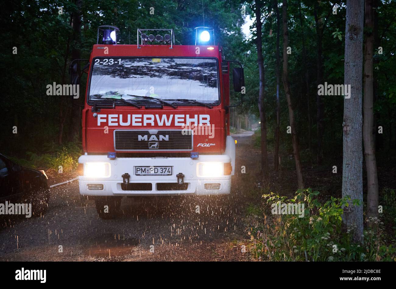 Treuenbrietzen, Deutschland. 20.. Juni 2022. Das blaue Licht eines Feuerwehrmotors leuchtet, wenn er im frühen Morgenregen in einem Waldstück zwischen Treuenbriezen und Beelitz steht. Nur etwa 20 Kilometer voneinander entfernt brannten am Wochenende zwei große Waldgebiete in der Nähe von Treuenbrietzen und Beelitz (beide im Landkreis Potsdam-Mittelmark). Die Lage beim Waldbrand bei Treuenbrietzen, der etwa 80 Kilometer südwestlich von Berlin und 40 Kilometer von Potsdam entfernt liegt, war nach Einschätzung des Landkreises ab späten Sonntagabend stabil. Quelle: Annette Riedl/dpa/Alamy Live News Stockfoto