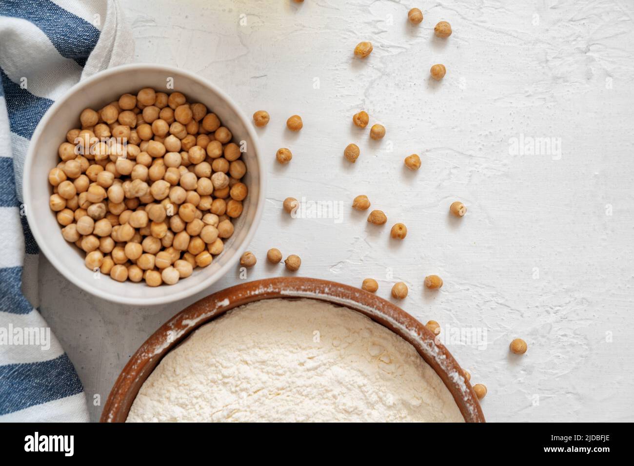 Kichererbsen und Mehl in Keramikschale auf weißem Hintergrund Stockfoto