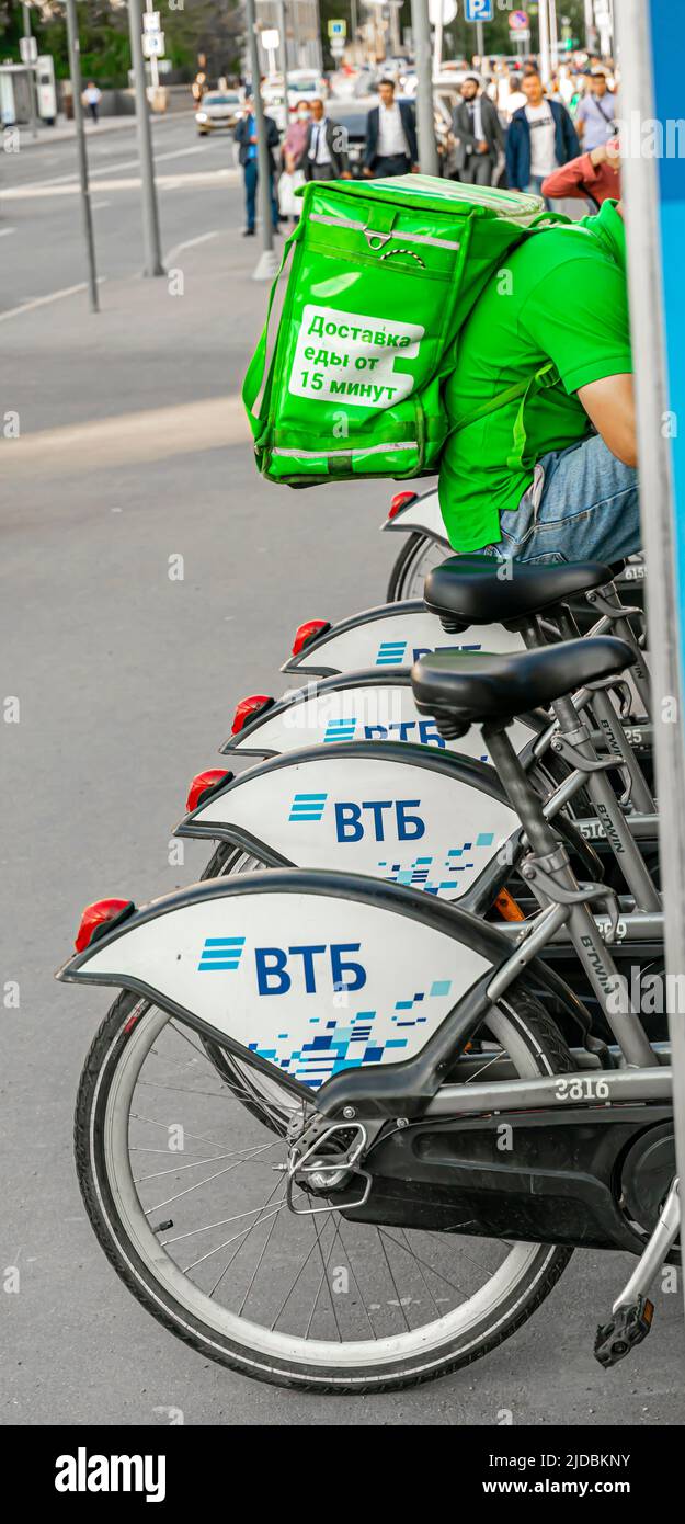 VTB geteilte Fahrräder Rechen mit Fahrrädern. Delivery Person sitzt auf einem Fahrrad Stockfoto