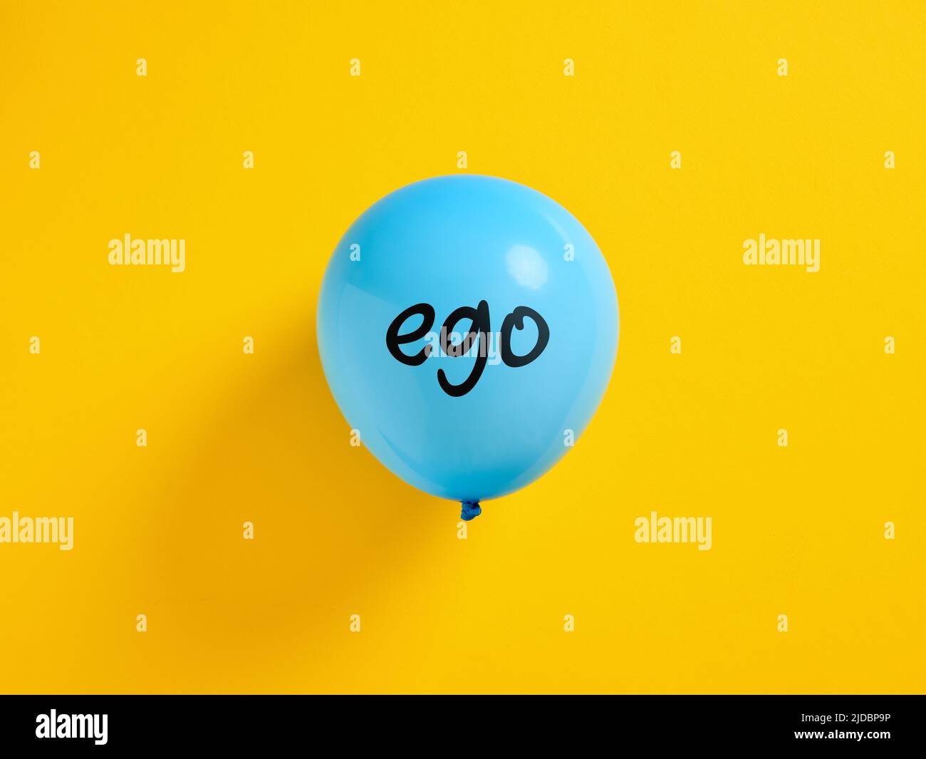 Aufgeblähter blauer Ballon mit dem Wort Ego und einer Nadel. Egoismus oder überhöhtes extremes Ego-Konzept. Stockfoto