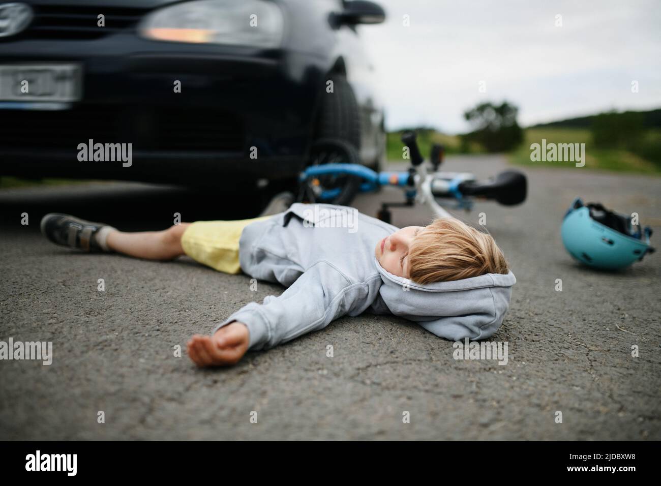 Kleiner Junge fiel vom Fahrrad und lag nach einem Autounfall noch auf der Straße. Stockfoto