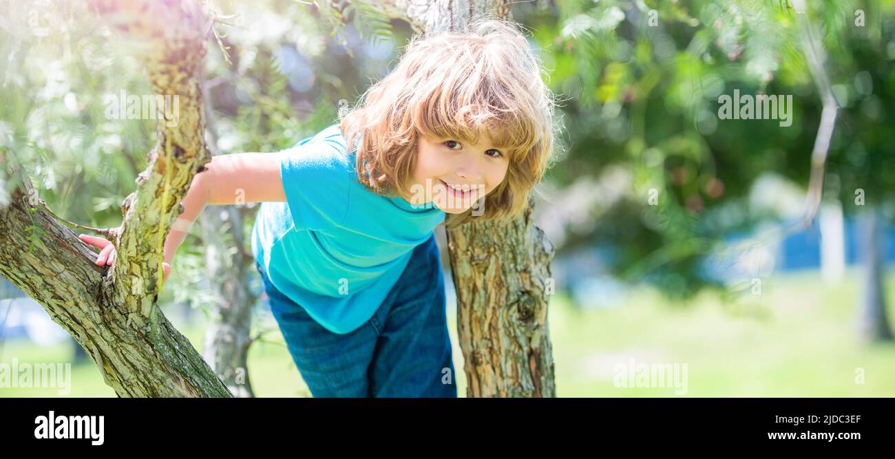 Bäume zu klettern macht immer Spaß. Aktiver Junge Kind klettert Baum. Spaß für die Kindheit. Aktivurlaub im Sommer. Horizontales Posterdesign. Web-Banner-Header, Kopierbereich. Stockfoto