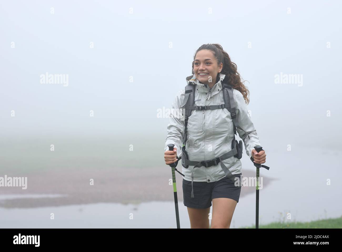 Vorderansicht Porträt eines glücklichen Wanderers, der in einem nebligen Berg läuft Stockfoto