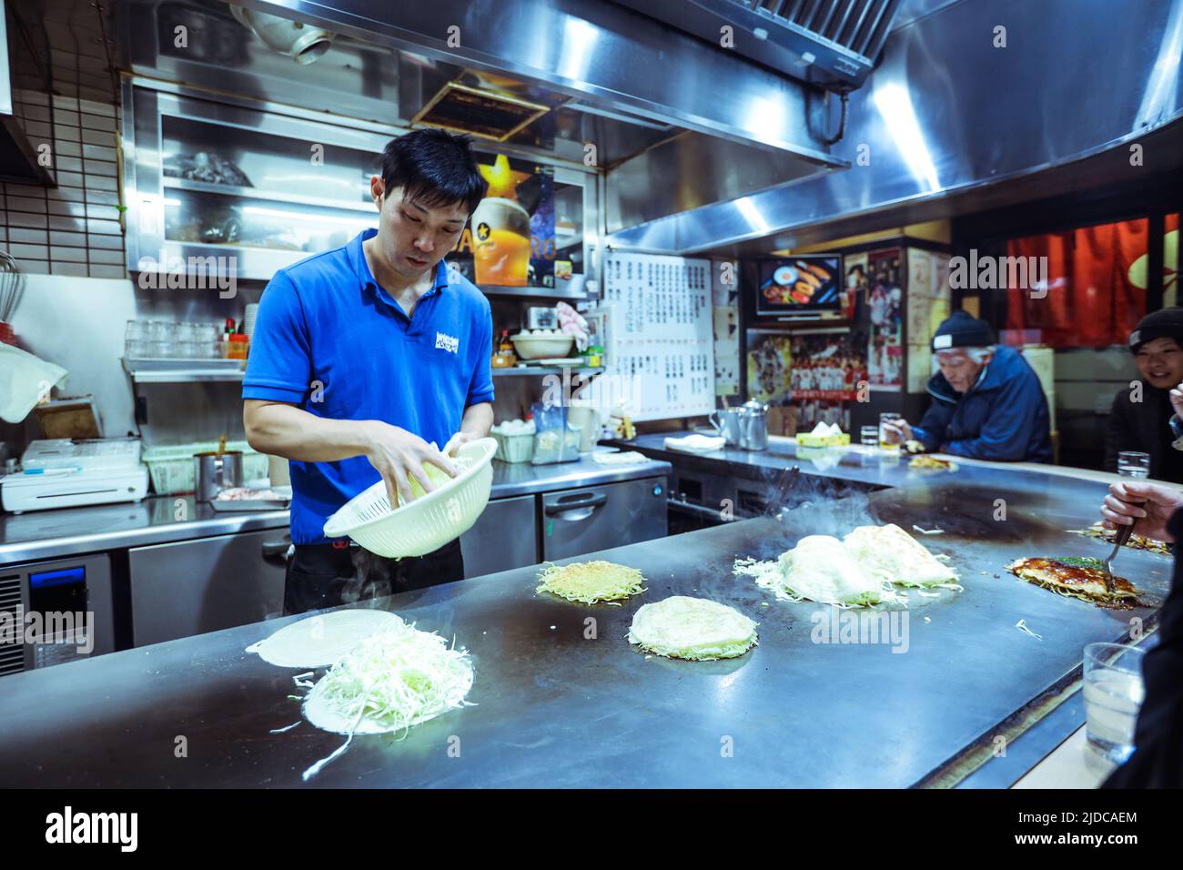 Lokaler Koch bereitet das typische japanische Gericht Okonomiyaki im Hiroshima Restaurant, Japan, zu Stockfoto