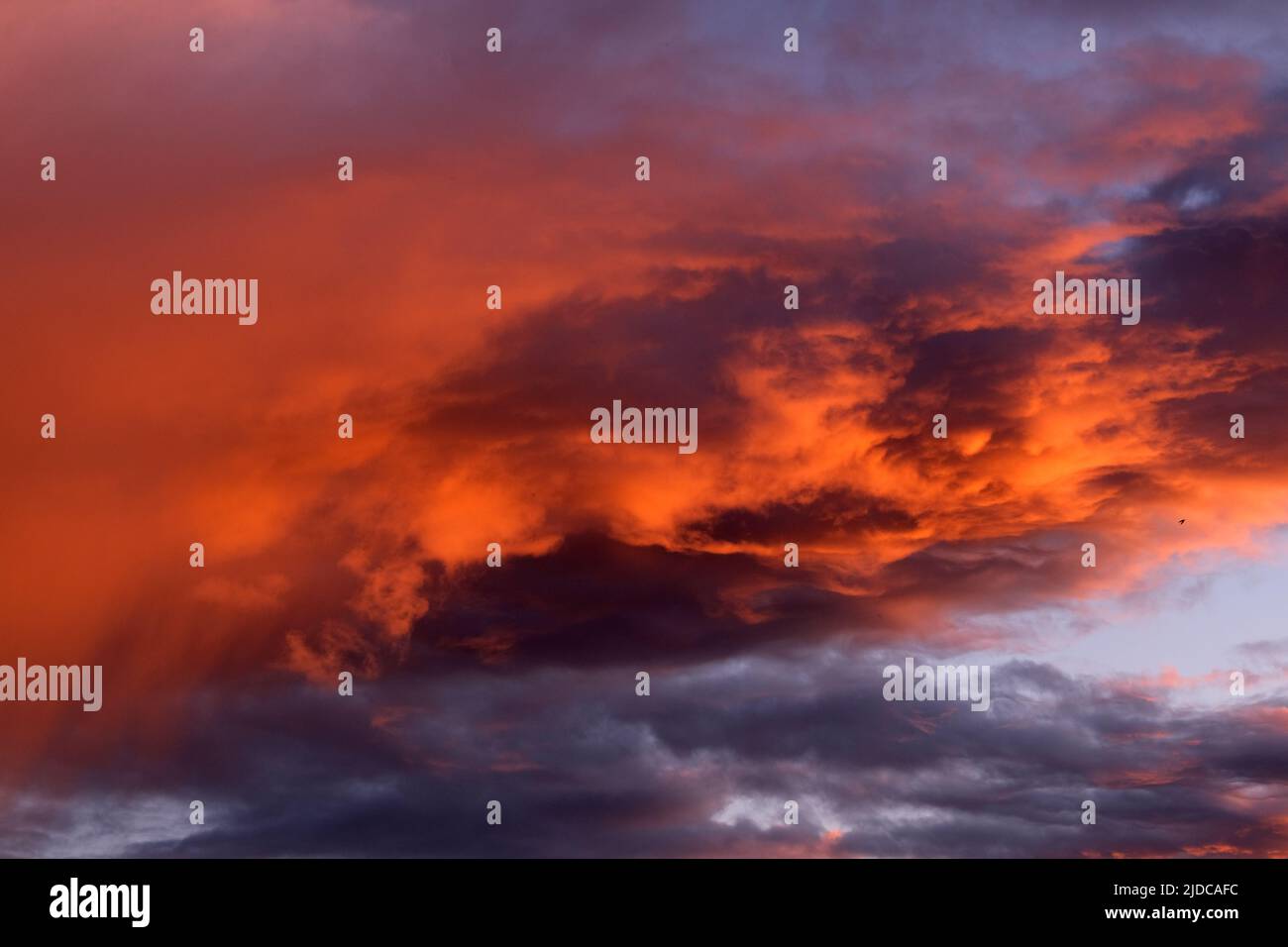 Die Wolken werden leuchtend orange, wenn die letzten Sonnenstrahlen auf sie treffen, während sich eine vorbeiziehende Kaltfront über das Murray Darling Basin bewegt. Stockfoto