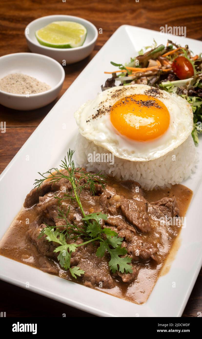 Traditionelles kambodschanisches Lok Lak Rührbraten mit Reisgericht auf Holztisch Hintergrund Stockfoto