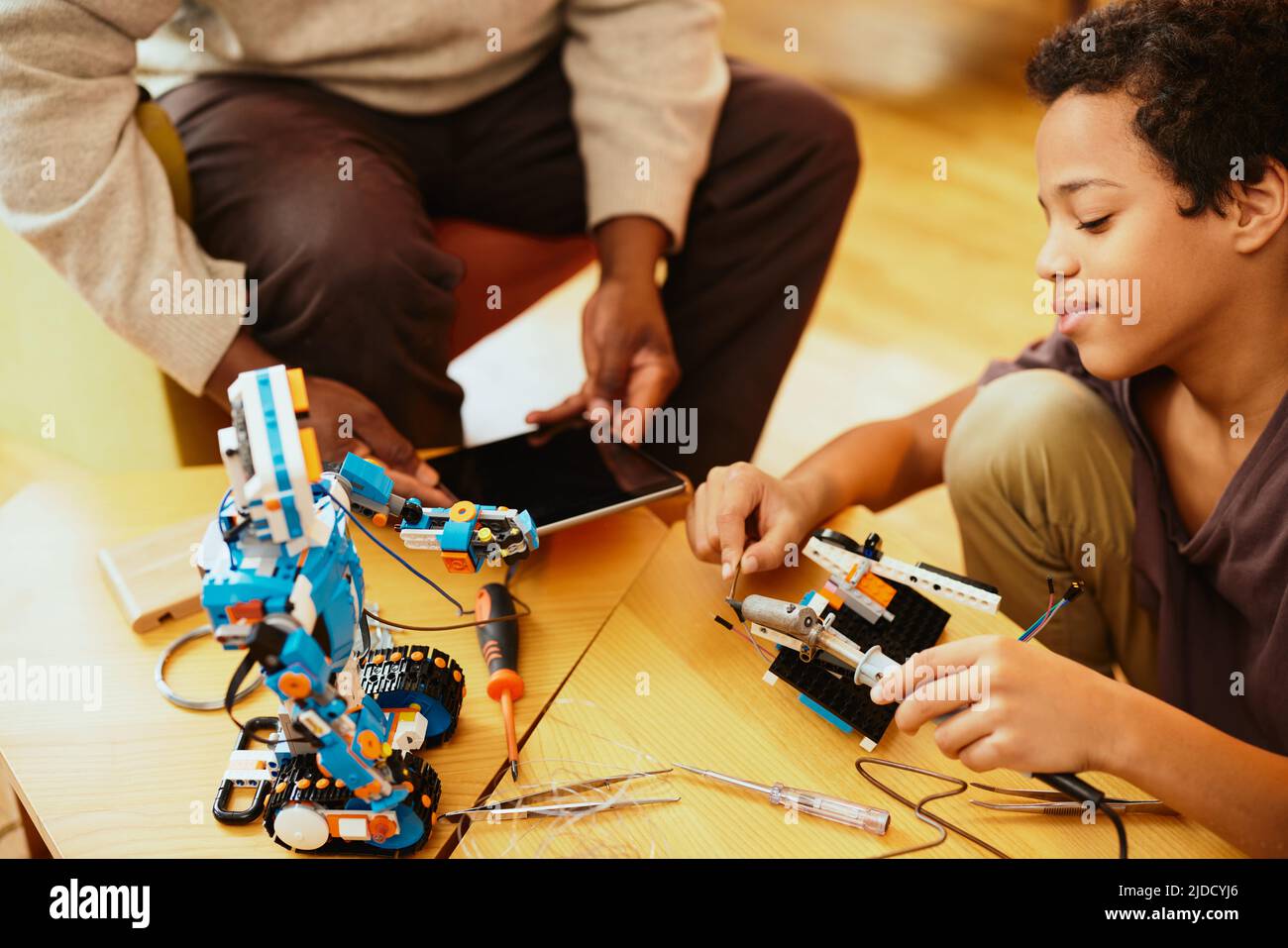 Ein Großvater und sein Enkelkind bauen zu Hause einen Roboter. Stockfoto