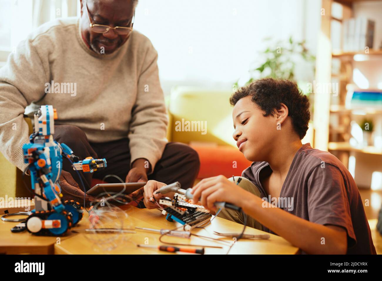 Ein Großvater und sein Enkelkind bauen zu Hause einen Roboter. Stockfoto