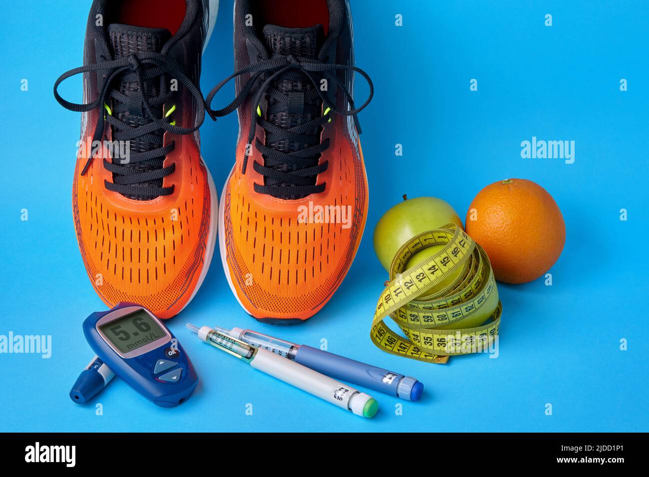 Orangefarbene Sneakers, Früchte, Maßband, Glucometer und Insulin-Spritzenstifte auf blauem Hintergrund. Bewegung, Ernährung und Diabetes-Management Stockfoto