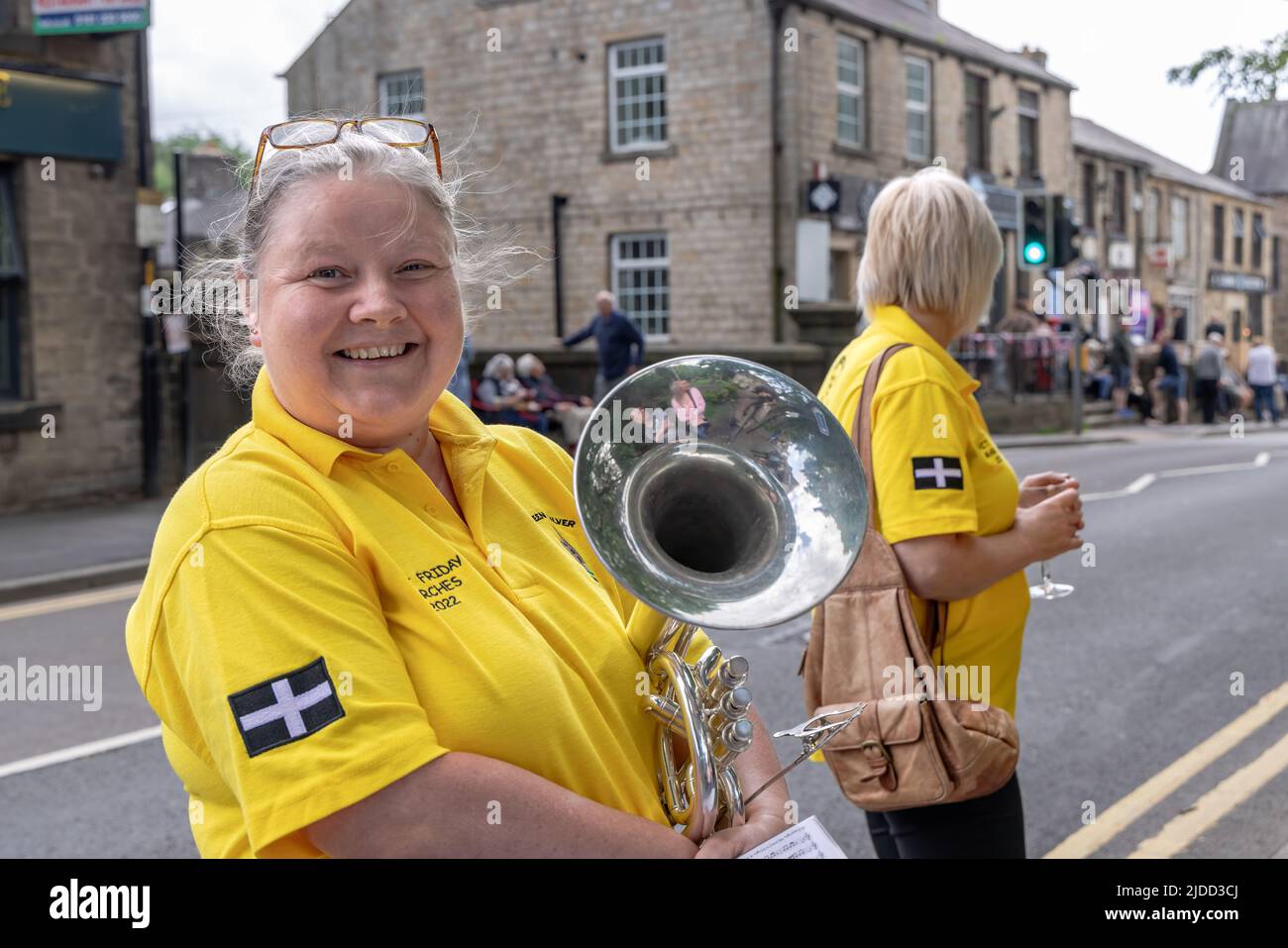 Fröhlich lächelnde Musikerin auf der Straße beim Uppermill Brass Band Pfingstfreitagswettbewerb in Saddleworth, England. Stockfoto