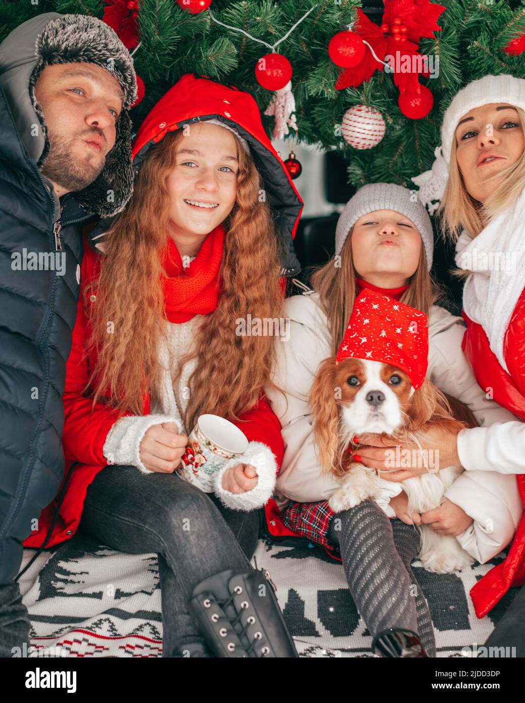 Glückliche Familie Vater Mutter 2 Mädchen geben Ihnen weht Kuss. Weihnachtsfeier im Auto LKW. Rote Weihnachtsdekoration. Fröhliche Stimmung. Glück. Stockfoto