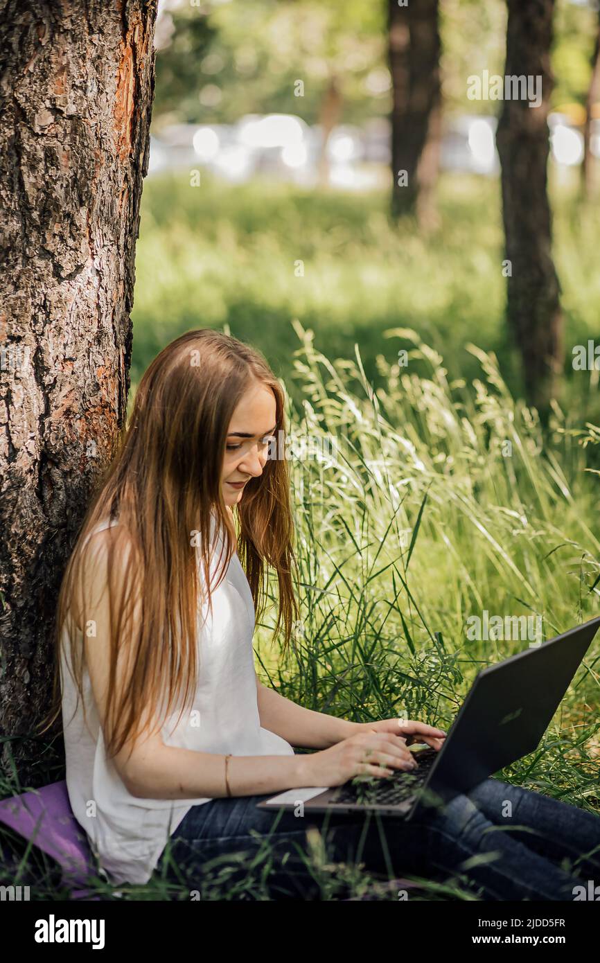 Junge Geschäftsfrau, die am Computer im Café auf dem Felsen arbeitet. Junges Mädchen downshifter arbeitet an einem Laptop bei Sonnenuntergang oder Sonnenaufgang auf der Spitze des Berges zum Meer, Arbeitstag Stockfoto