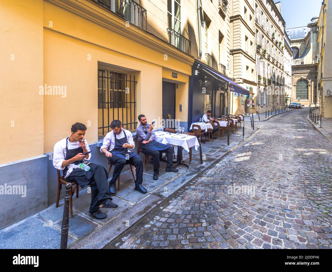 Kellner, die sich vor dem Mittagessen vor dem Restaurant entspannen - Rue Servandoni, Paris 6, Frankreich. Stockfoto