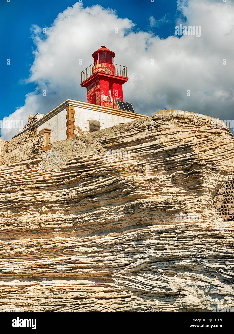 Dieser leuchtend rote Leuchtturm steht hoch auf einem felsigen Punkt außerhalb des Hafens von Bonifacio. Stockfoto