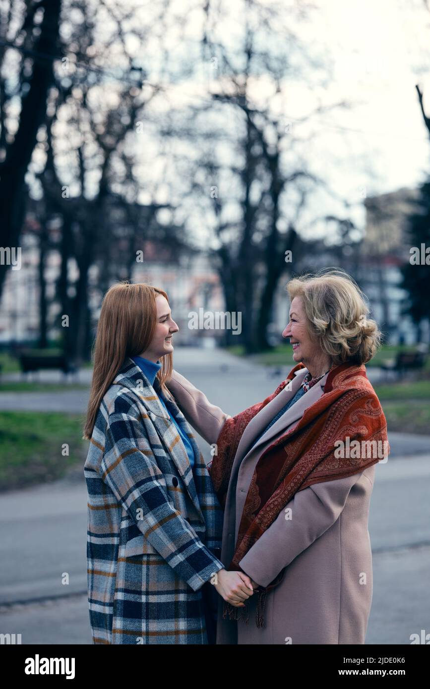 Eine Großmutter, die sich mit ihrer Enkelin verklebte, während sie stand und die Hände hielt. Stockfoto