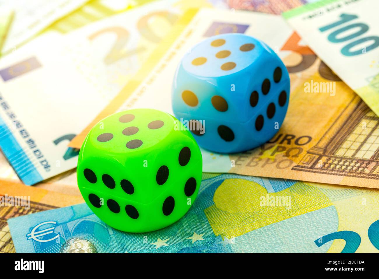 Bunte Würfel aus der Nähe auf einem Hintergrund von Euro-Banknoten. Geschäftsmöglichkeit und Risikokonzept. Stockfoto
