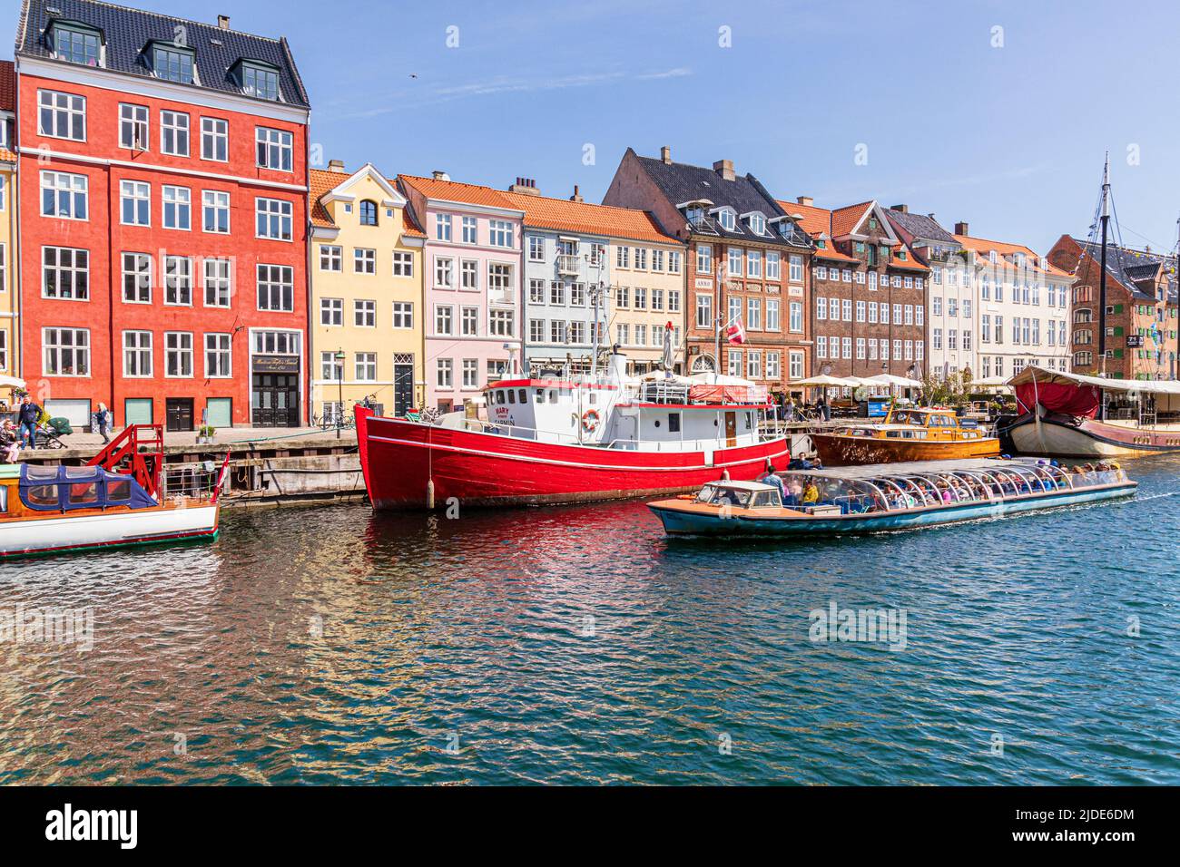 Ein Touristenboot, das Nyhavn, die farbenfrohe Kanalpromenade aus dem 17.. Jahrhundert in Kopenhagen, Dänemark, passiert. Stockfoto