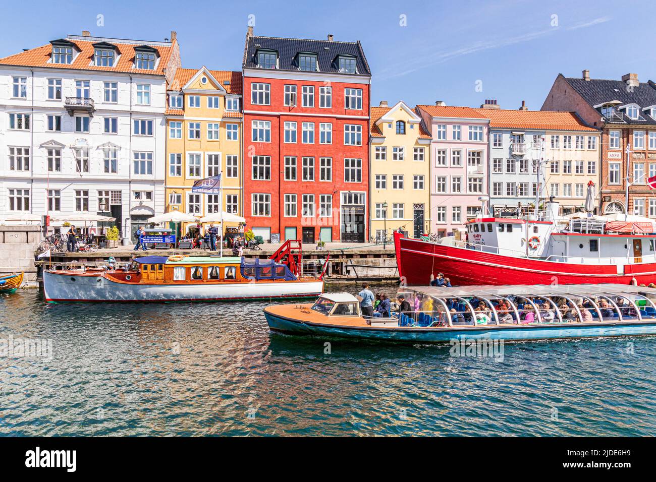 Ein Touristenboot, das Nyhavn, die farbenfrohe Kanalpromenade aus dem 17.. Jahrhundert in Kopenhagen, Dänemark, passiert. Stockfoto