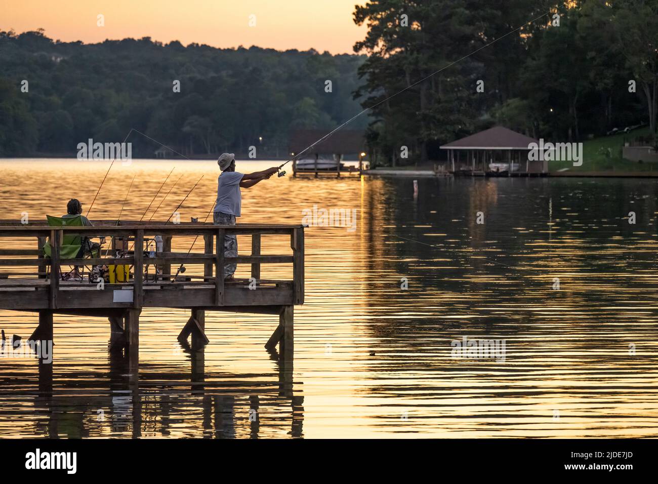 Paar Angeln von einem Fischerdock bei Sonnenuntergang am Lake Oliver, einem Stausee über Oliver Dam zwischen Columbus, Georgia und Phenix City, Alabama. (USA) Stockfoto