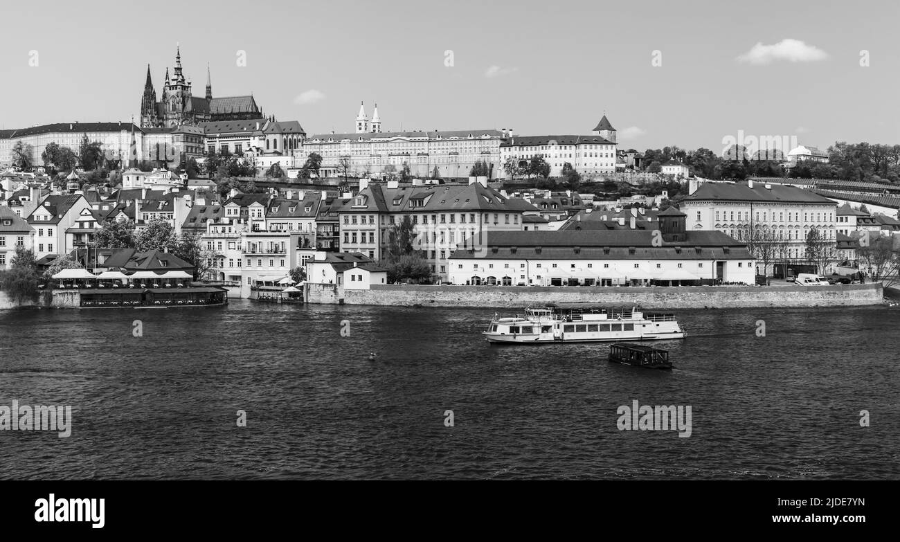 Blick auf das alte Prag an einem Sommertag. Tschechische Republik. Panorama-Schwarzweißfoto. Touristenboot fährt auf der Moldau Stockfoto