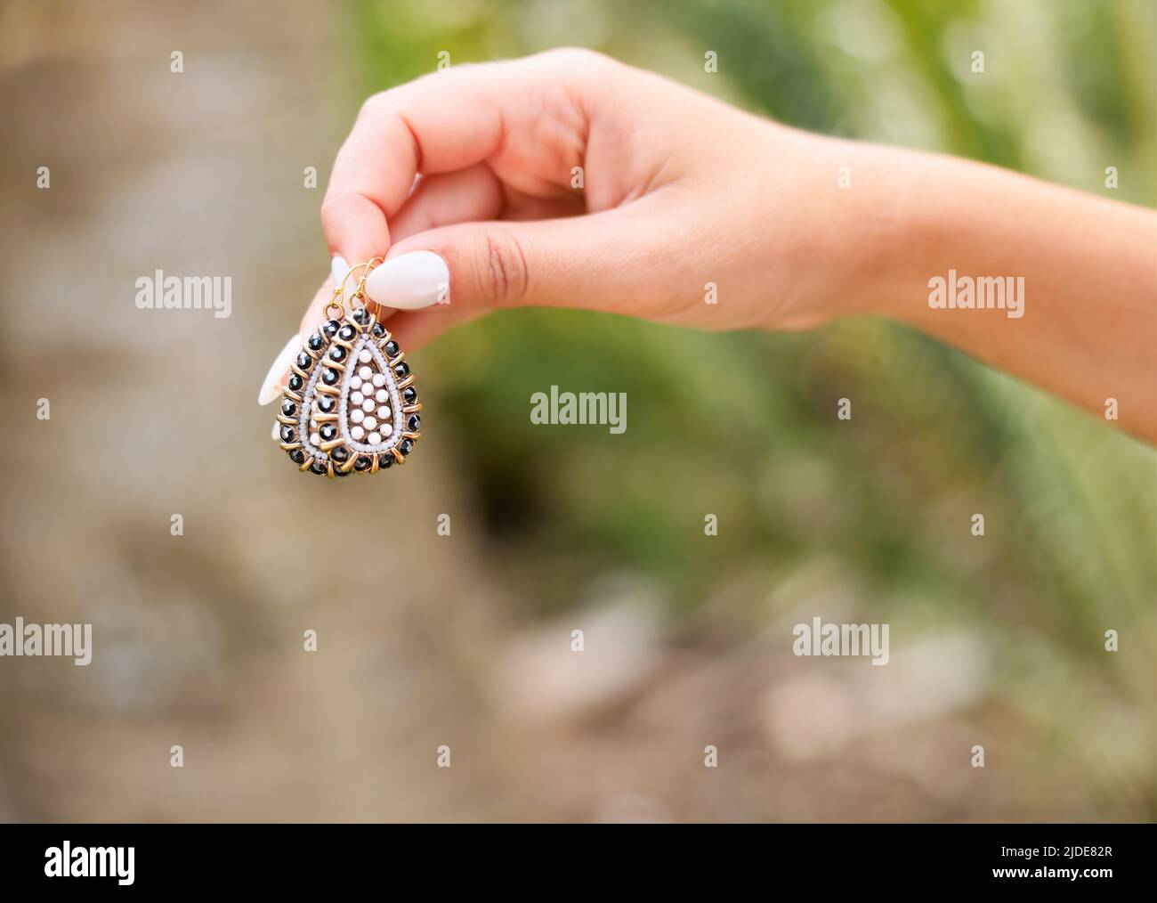 Handgefertigte Ohrringe mit Perlen in hoher Qualität mit schönen, von den Händen gepflegten Nägeln Stockfoto